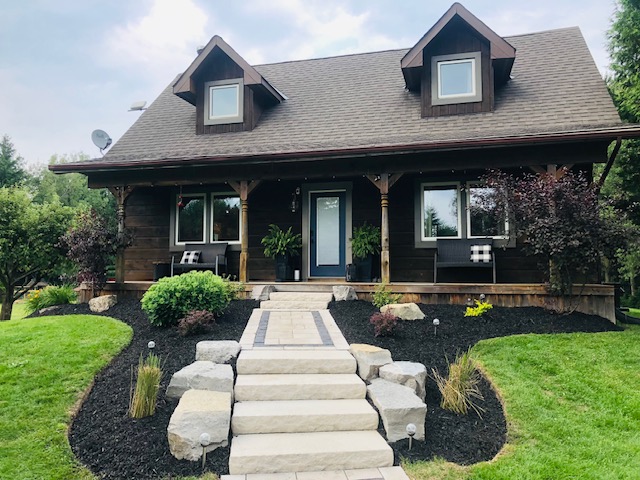 Manicured lawn, garden beds and custom stone walkway at a country cottage in Dufferin County
